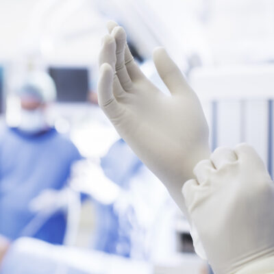 Close-up of surgeon putting on surgical gloves in operating theater